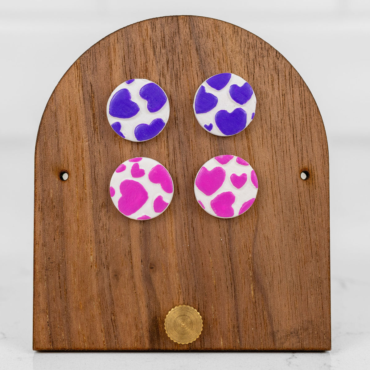 Round handmade polymer clay stud earrings with a sweet pink heart print pattern for Valentine's Day