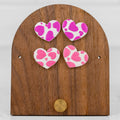 Heart-shaped handmade polymer clay stud earrings in pink with a playful all-over heart print pattern