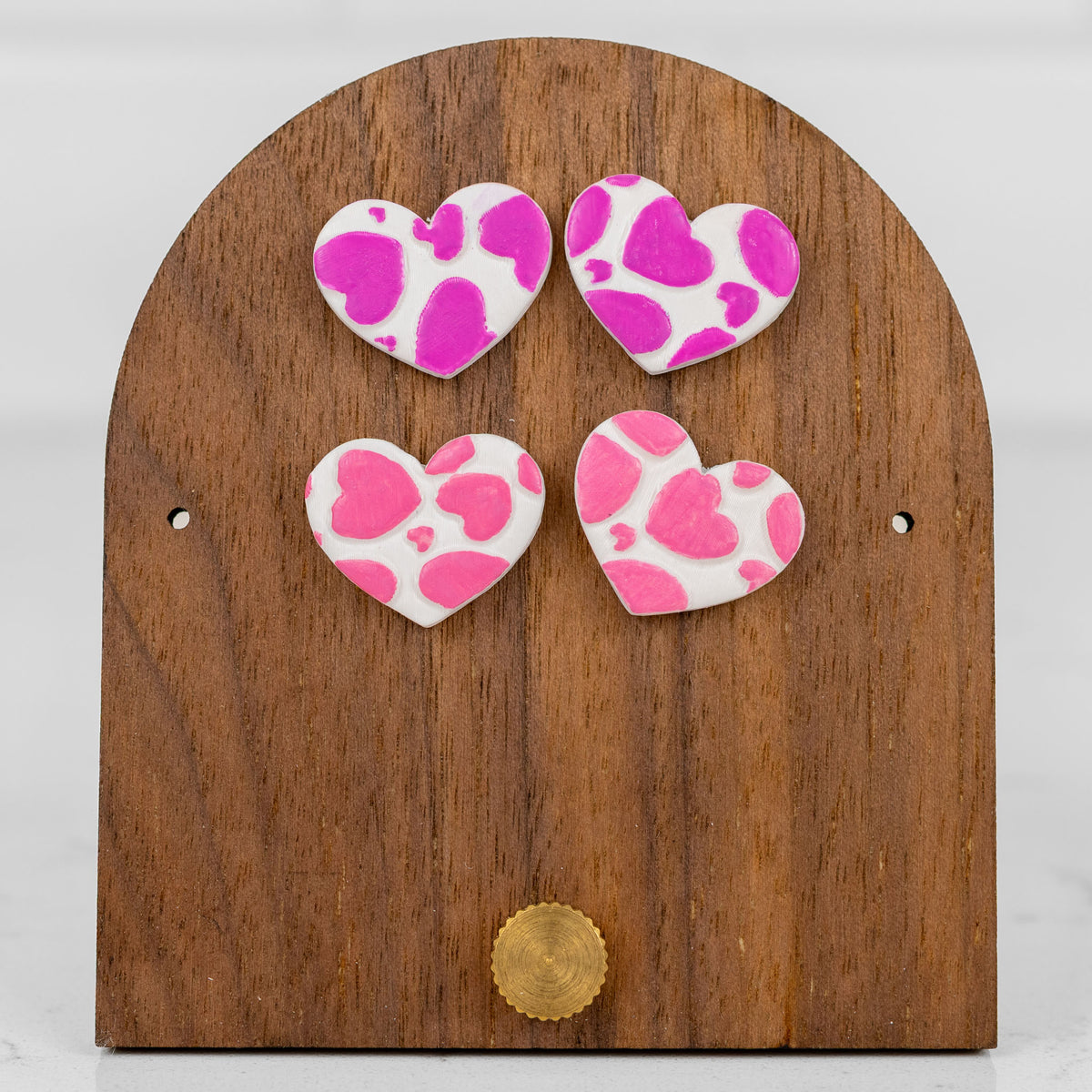 Heart-shaped handmade polymer clay stud earrings in pink with a playful all-over heart print pattern