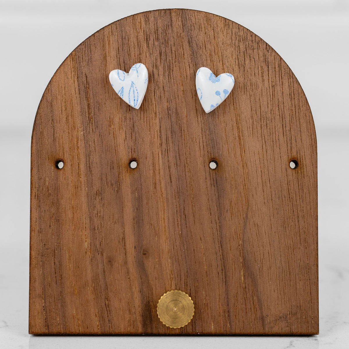 Petite heart-shaped handmade polymer clay stud earrings in white with a small blue floral pattern