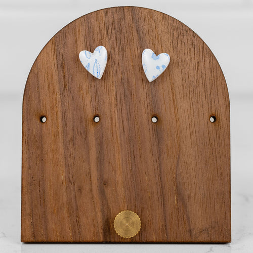 Petite heart-shaped handmade polymer clay stud earrings in white with a small blue floral pattern