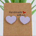 Heart-shaped earrings on a 'Handmade with Love' card with a plant in the background