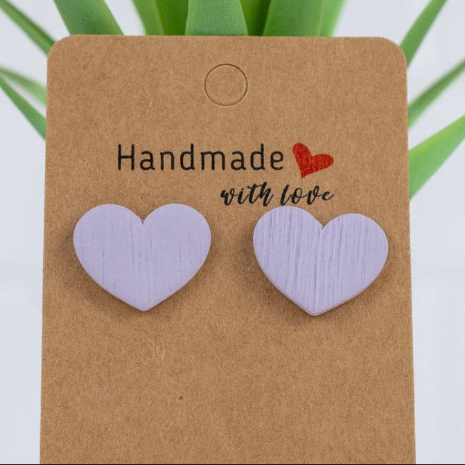 Heart-shaped earrings on a 'Handmade with Love' card with a plant in the background