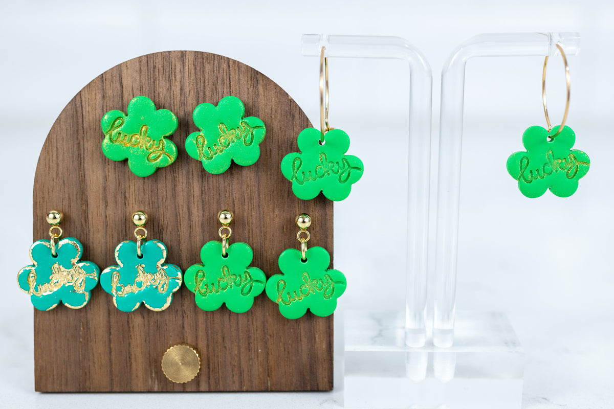 Handmade lucky shamrock polymer clay earrings in stud, dangle, and gold hoop styles with gold script detail