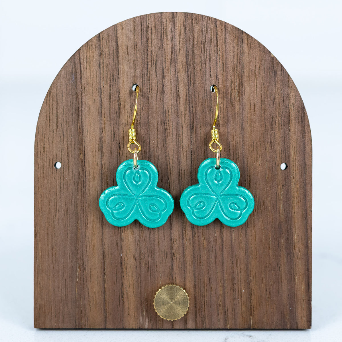 Teal shamrock polymer clay dangle earrings with embossed swirl detail and gold hooks