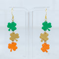 Triple shamrock polymer clay dangle earrings in green, gold, and orange with gold hooks